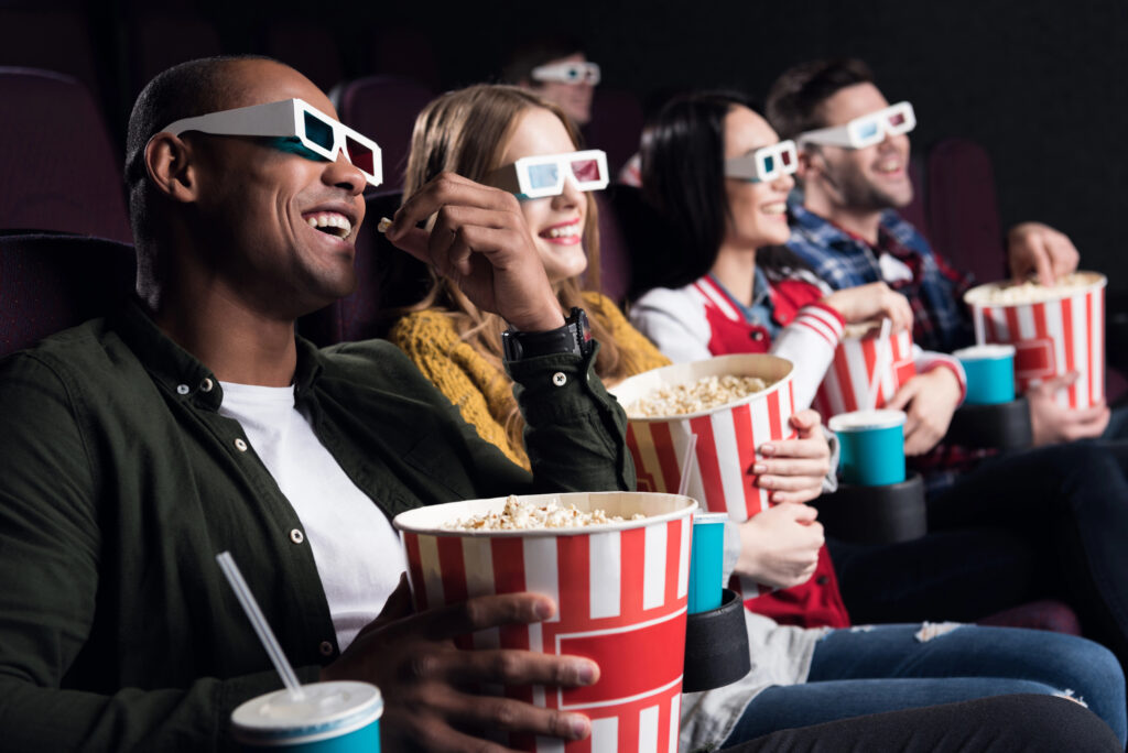 Amis riant au cinéma avec lunettes 3D et pop-corn