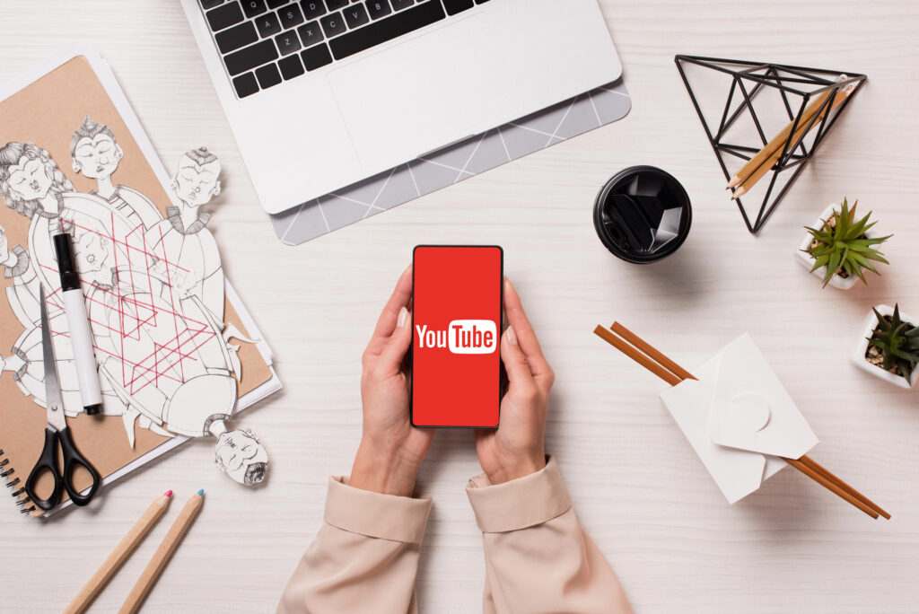 Mains tenant un smartphone affichant le logo YouTube