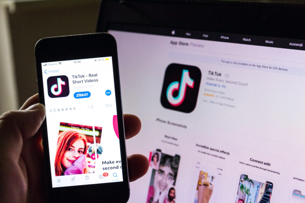 Un smartphone affichant l'application TikTok devant un écran d'ordinateur.