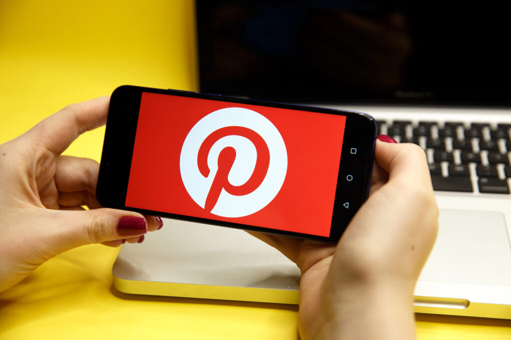 Mains tenant un smartphone affichant le logo de Pinterest