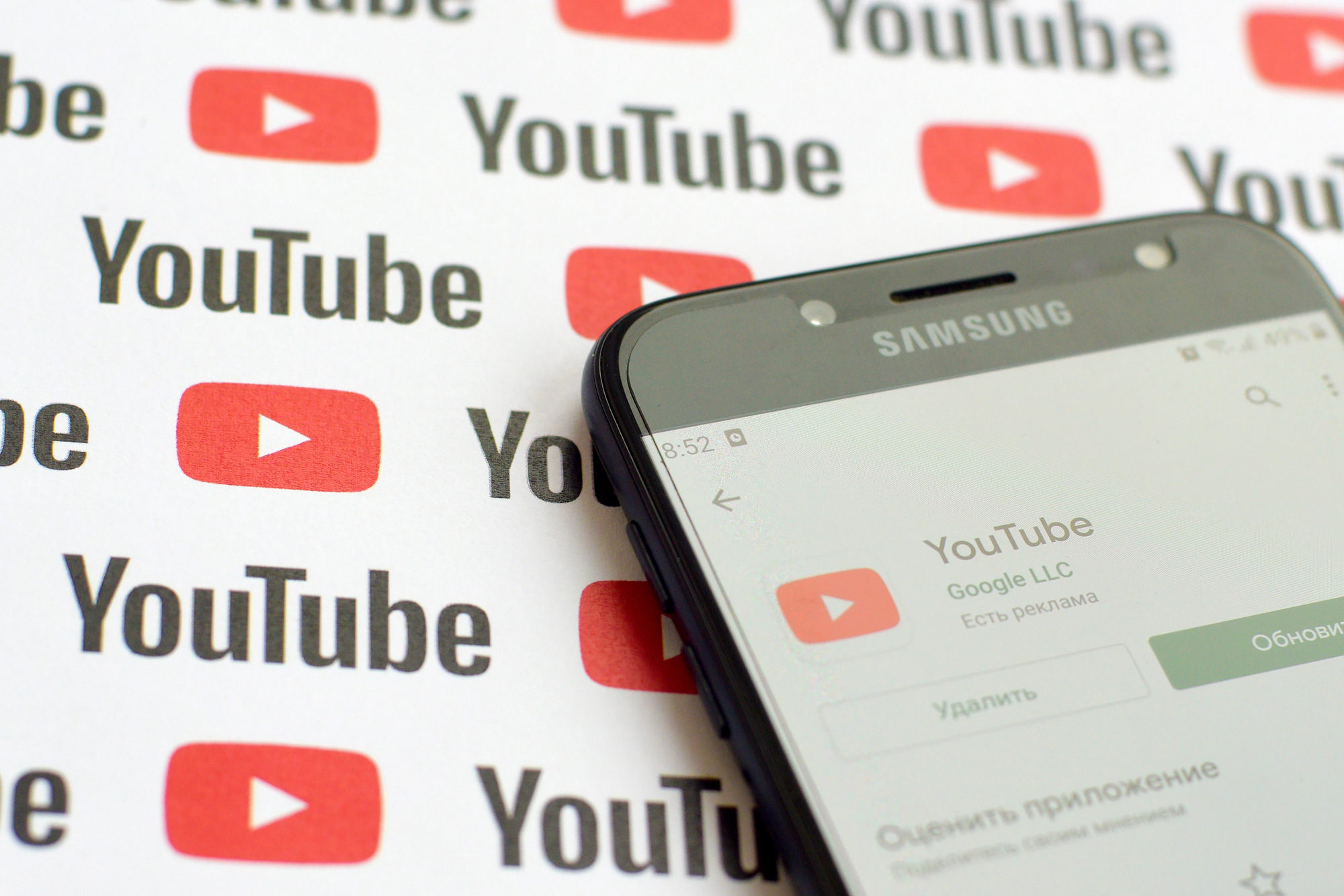 Smartphone affichant l'application YouTube sur un fond de logos