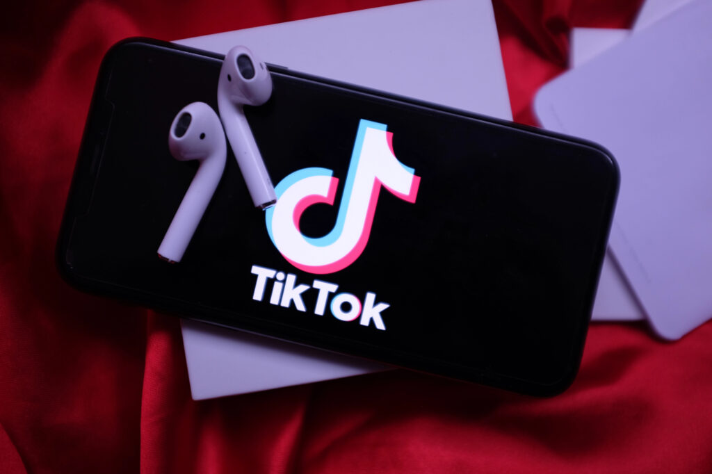 Logo TikTok sur smartphone avec écouteurs sans fil.
