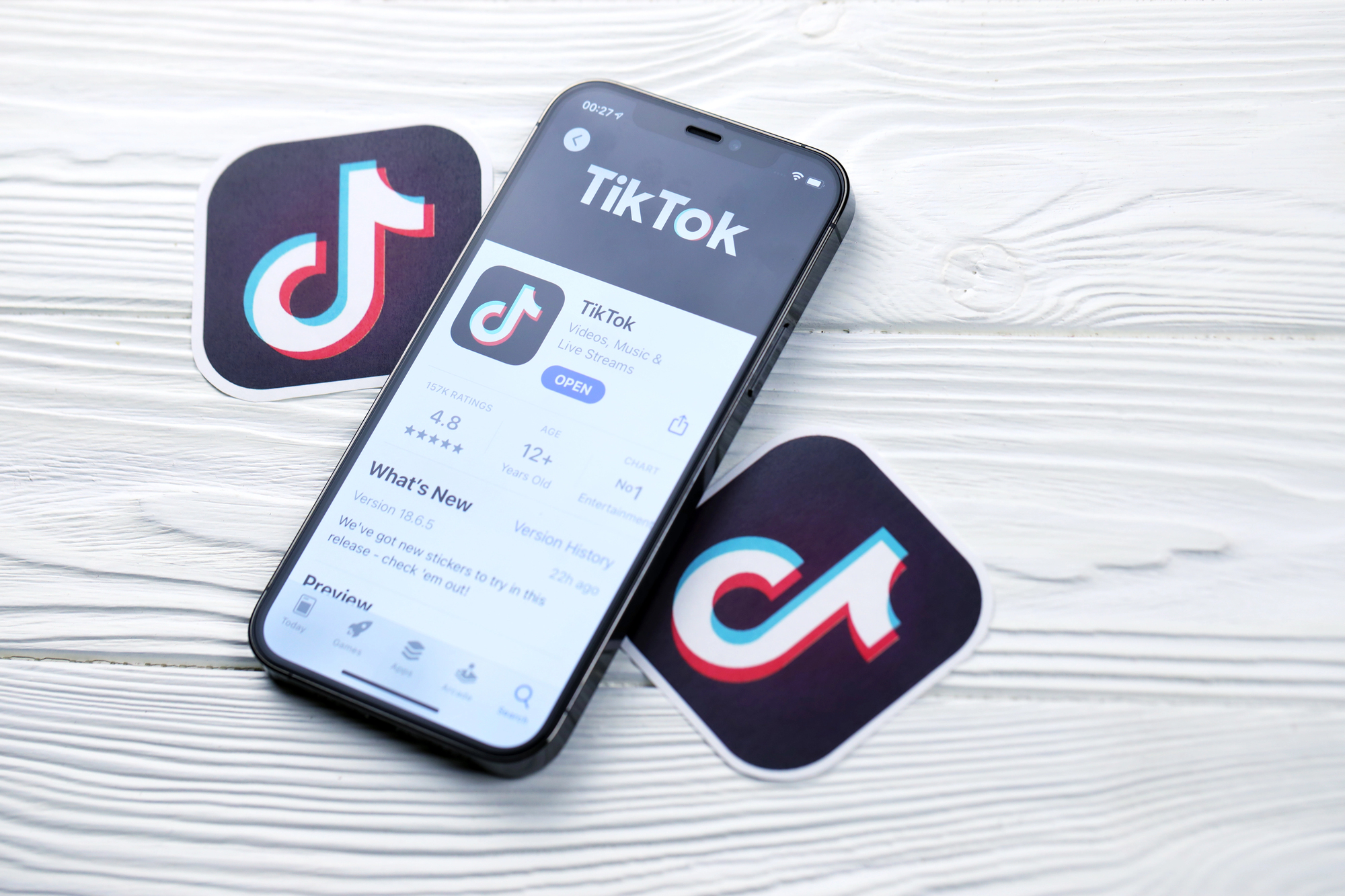 Smartphone affichant l'App Store avec TikTok sur fond bois