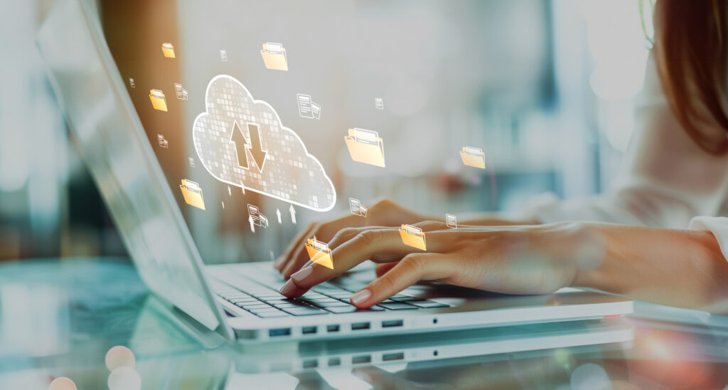 Mains tapant sur un ordinateur avec des icônes de cloud