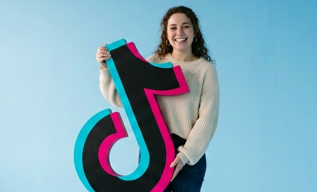 logo tiktok géant au centre d'une pièce rose vide.