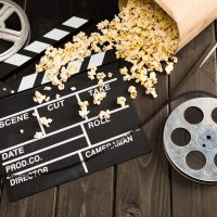 Claquette de cinéma, bobines de film et pop-corn renversés.