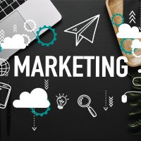 Mot « MARKETING » entouré d'icônes digitales sur un bureau