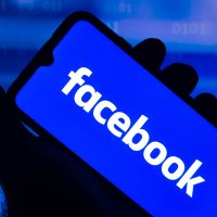 Smartphone affichant le logo blanc de Facebook sur fond bleu.