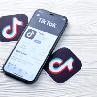 Smartphone affichant l'App Store avec TikTok sur fond bois