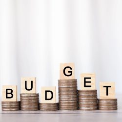 Des lettres épelant « BUDGET » sur des piles de pièces