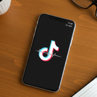 Un smartphone affichant TikTok sur un bureau en bois.