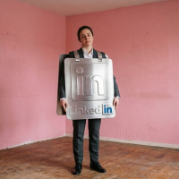femme portant un panneau linkedin en carton dans une pièce rose.