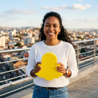 femme souriante tenant un logo snapchat sur un toit urbain.
