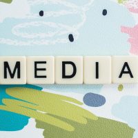 Lettres de jeu scrabble formant le mot "MEDIA" sur fond coloré.