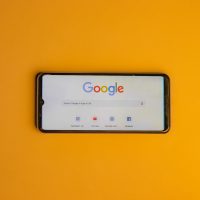 Smartphone affichant le moteur de recherche Google sur fond orange.