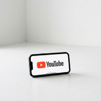 smartphone posé affichant le logo youtube sur fond blanc.
